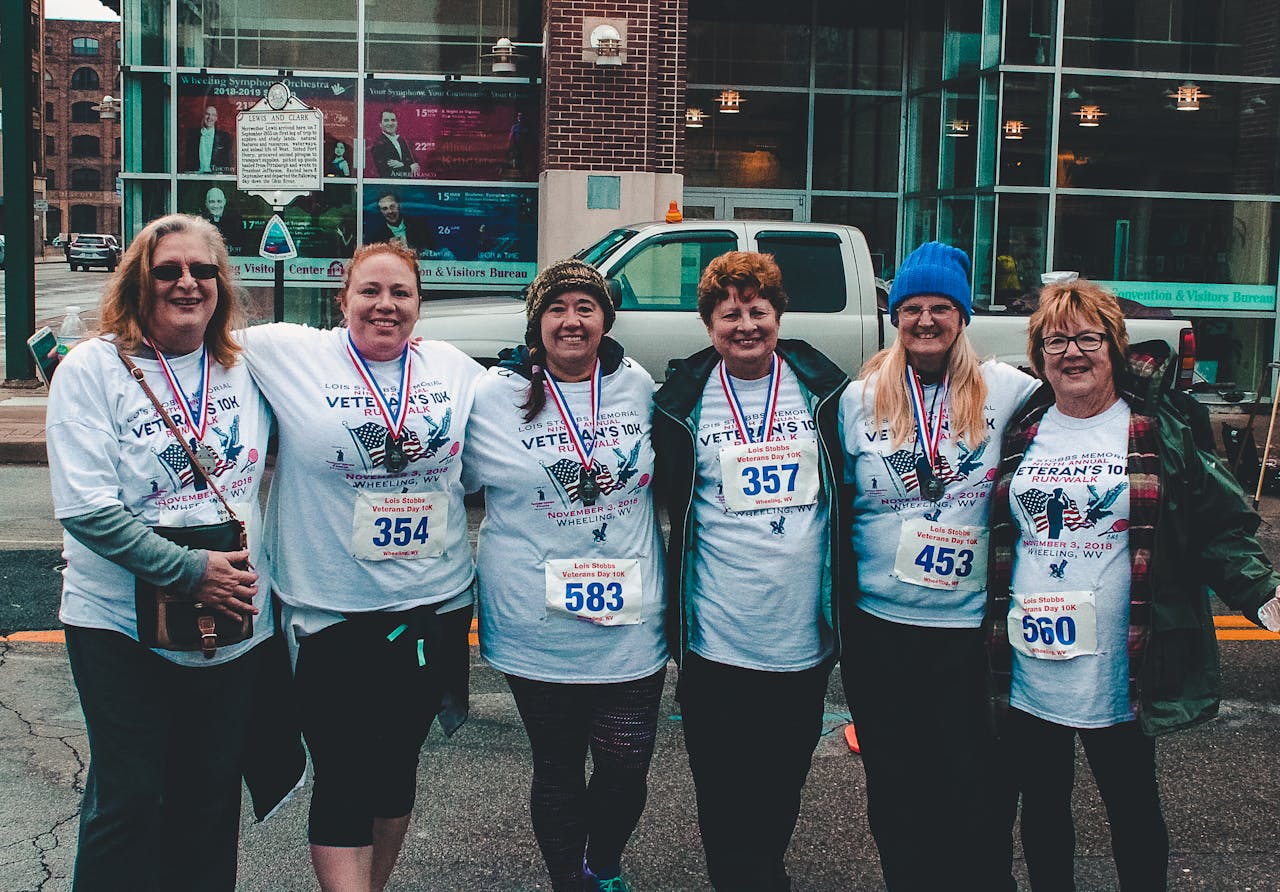 Six women participate in a Veterans Day 10K run wearing matching shirts and medals.