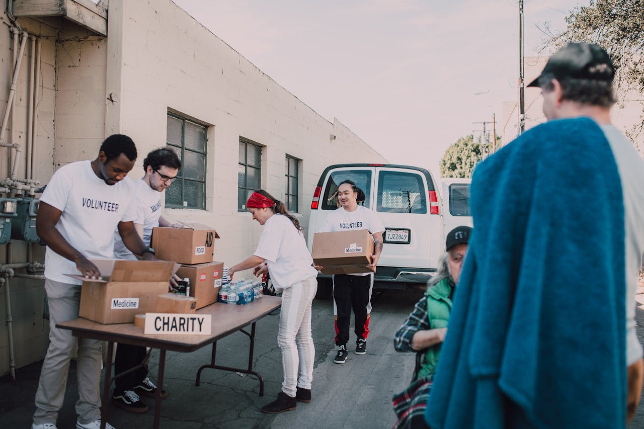 Group of volunteers organizing donations outside, showcasing diversity and teamwork.